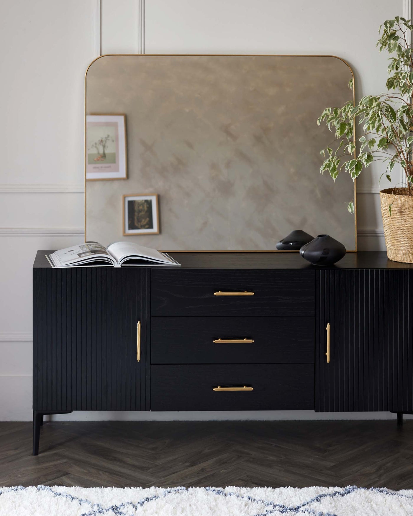 Elegant contemporary sideboard in black with textured front panels, featuring three drawers and two doors with brass handles, set on a slender black frame base.
