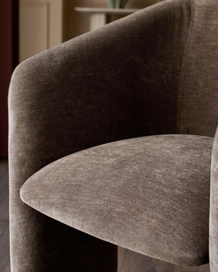 Leighton brushed bronze cantilever bar stool in mocha fabric, showing curved seat and backrest detail from side angle.