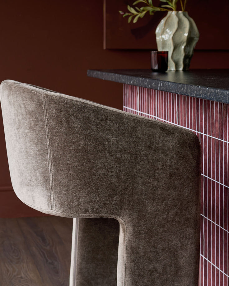 Leighton brushed bronze cantilever bar stool in mocha fabric, side view showing curved backrest and metal frame detail.