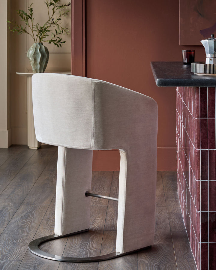 Leighton bar stool in natural grey fabric with black steel cantilever base, shown in modern interior setting.