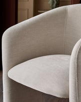 Cream fabric armchair with curved backrest and rounded seat, detailed close-up view showing textile weave and seam detailing.