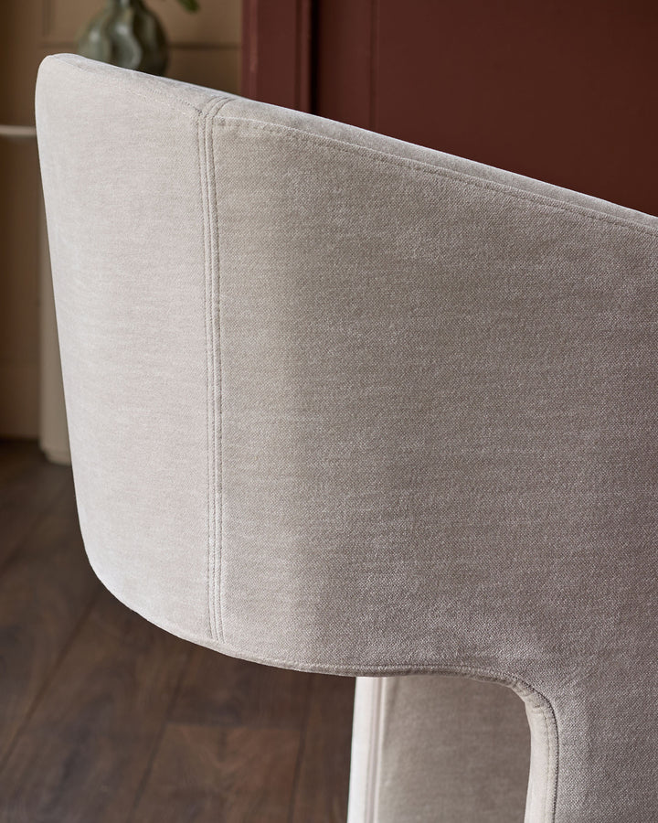 Leighton bar stool close-up showing natural grey fabric seat and white metal frame leg.