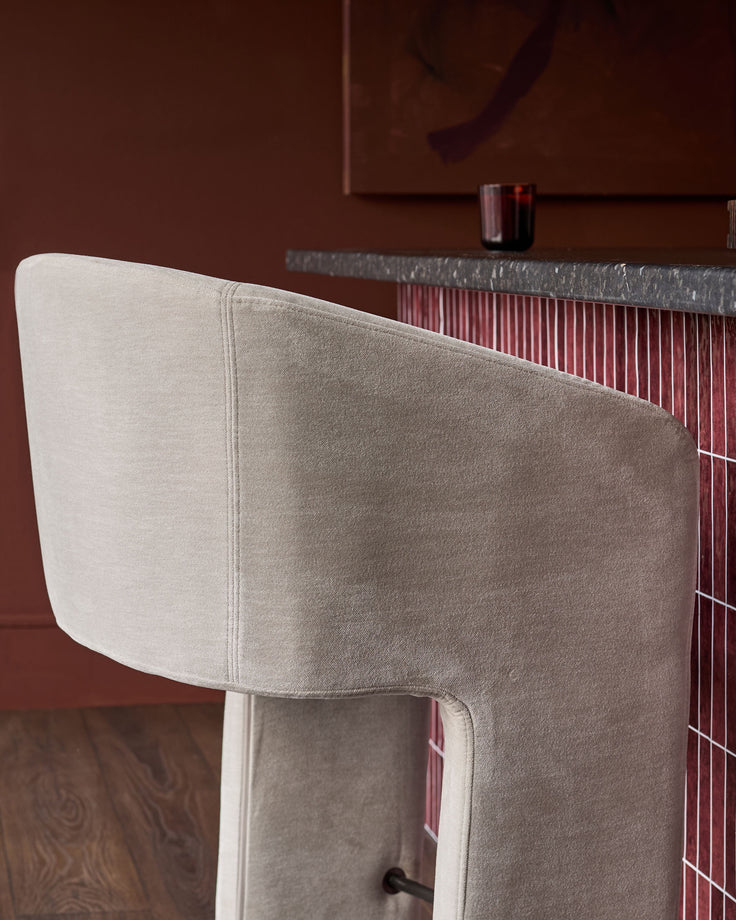 Leighton bar stool in natural grey fabric, side view showing curved backrest and cantilever steel frame design.