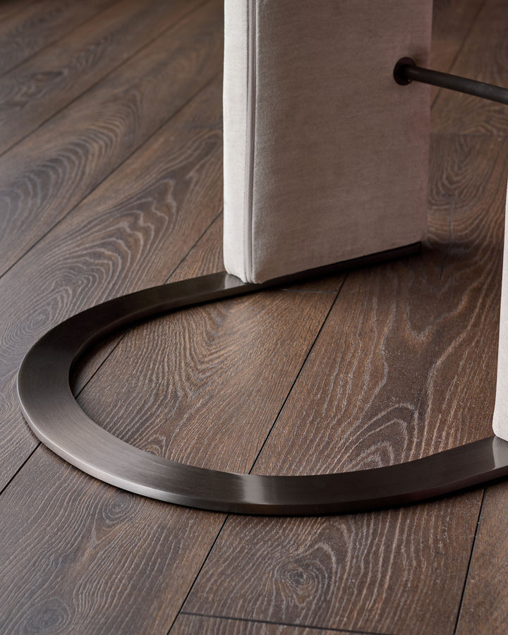Black steel cantilever bar stool base with curved footrest on wood flooring, showing modern design detail.