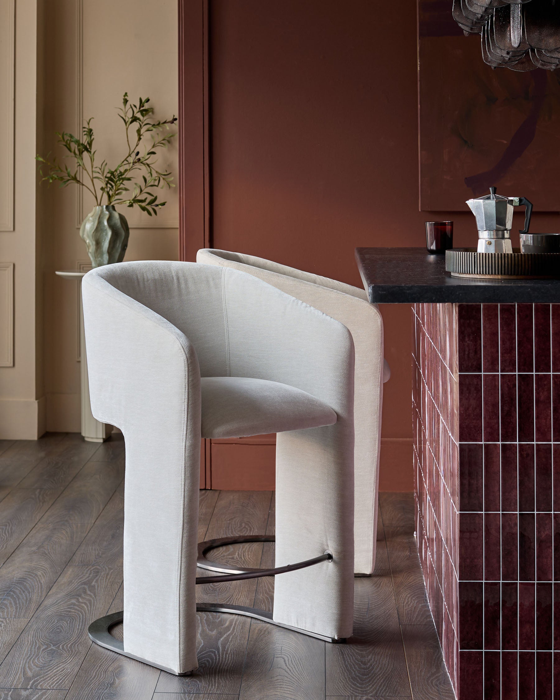 Leighton bar stool in natural grey fabric with black steel cantilever base, shown in modern interior setting.