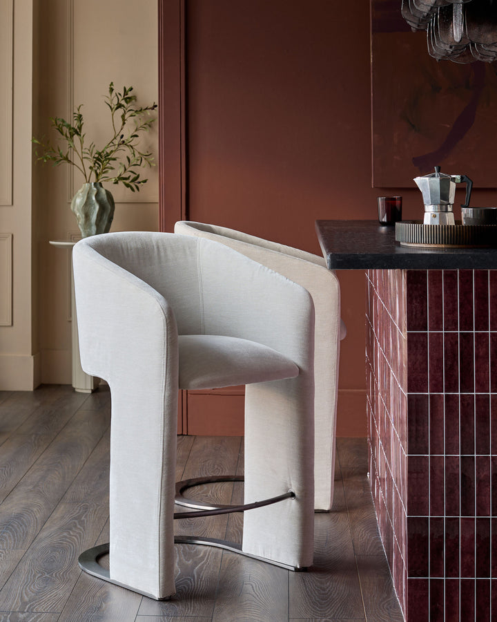 Leighton bar stool in natural grey fabric with black steel cantilever base, shown in modern interior setting.