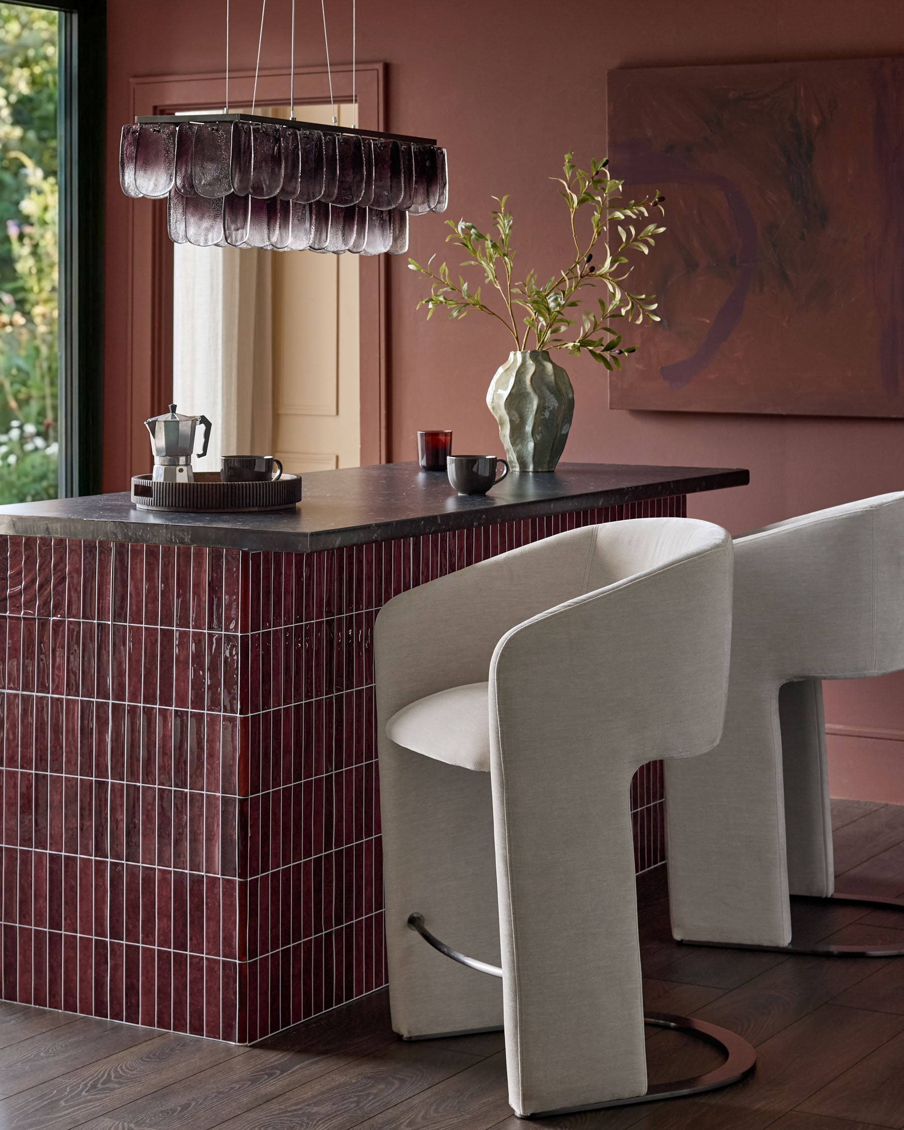 Leighton black steel cantilever bar stool in natural grey fabric, shown at burgundy kitchen island with modern curved backrest.
