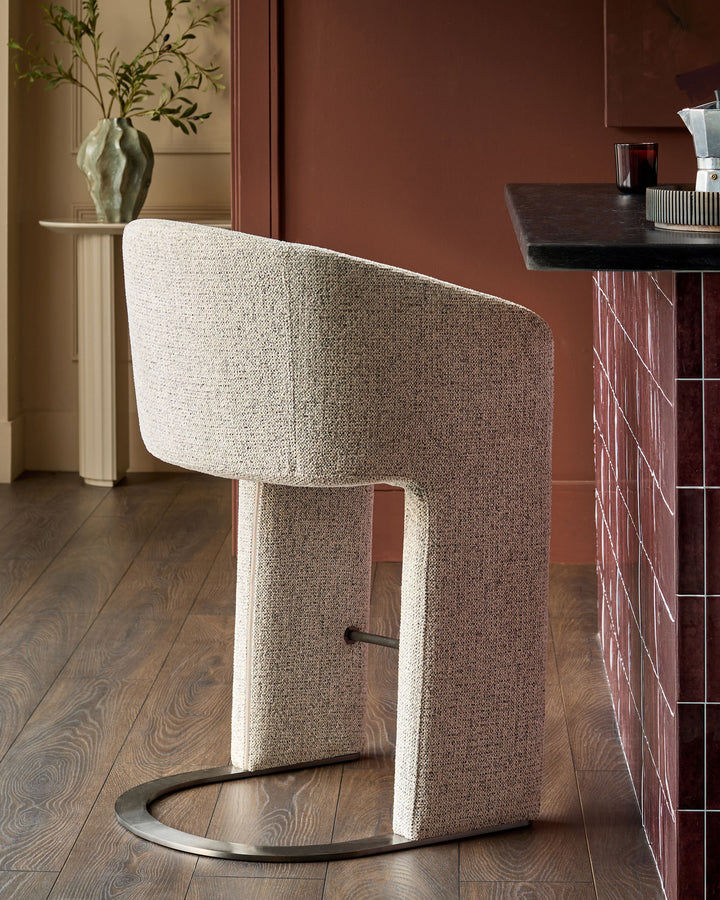 Leighton bar stool in grey fabric with black steel cantilever base, shown in modern interior setting.