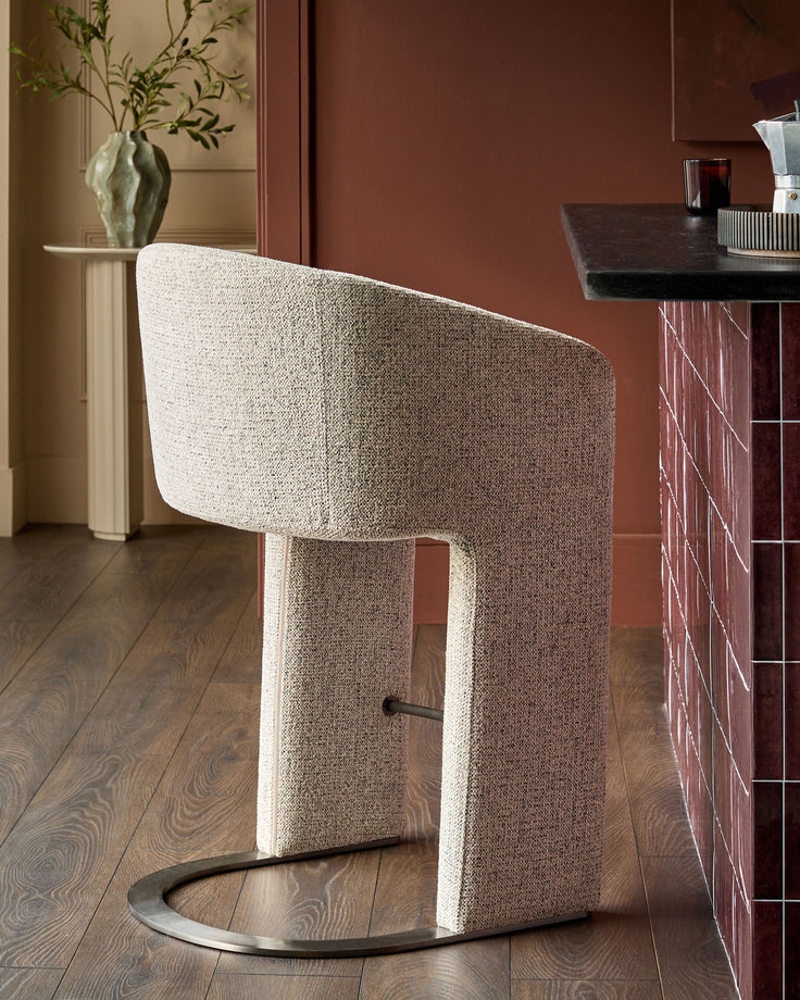Leighton bar stool in grey fabric with black steel cantilever base, shown in modern interior setting.
