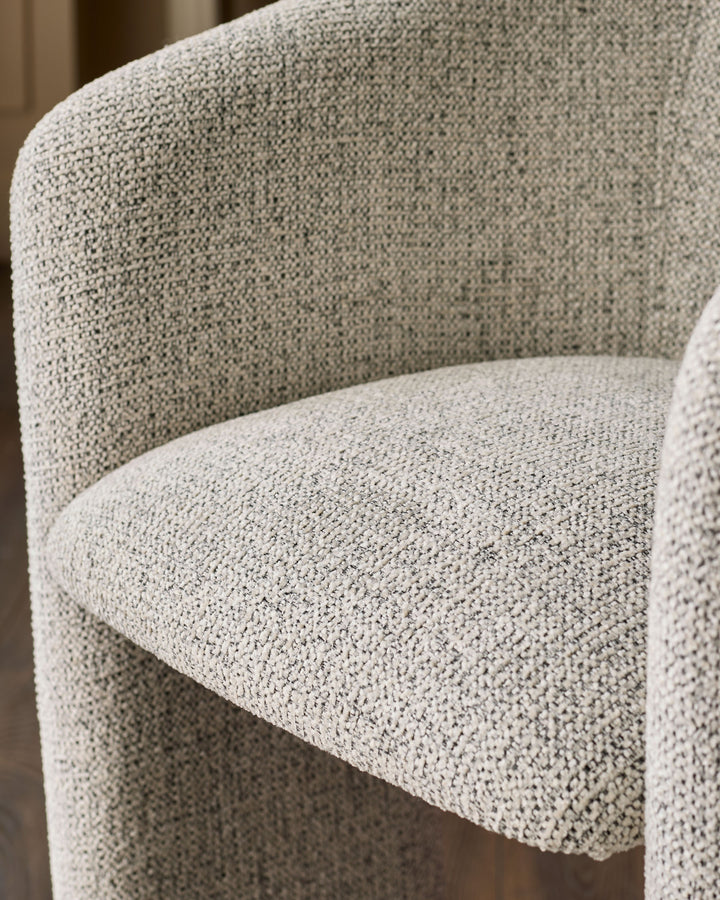 Close-up of grey fabric upholstery on a curved chair back and seat, showing woven textile detail.