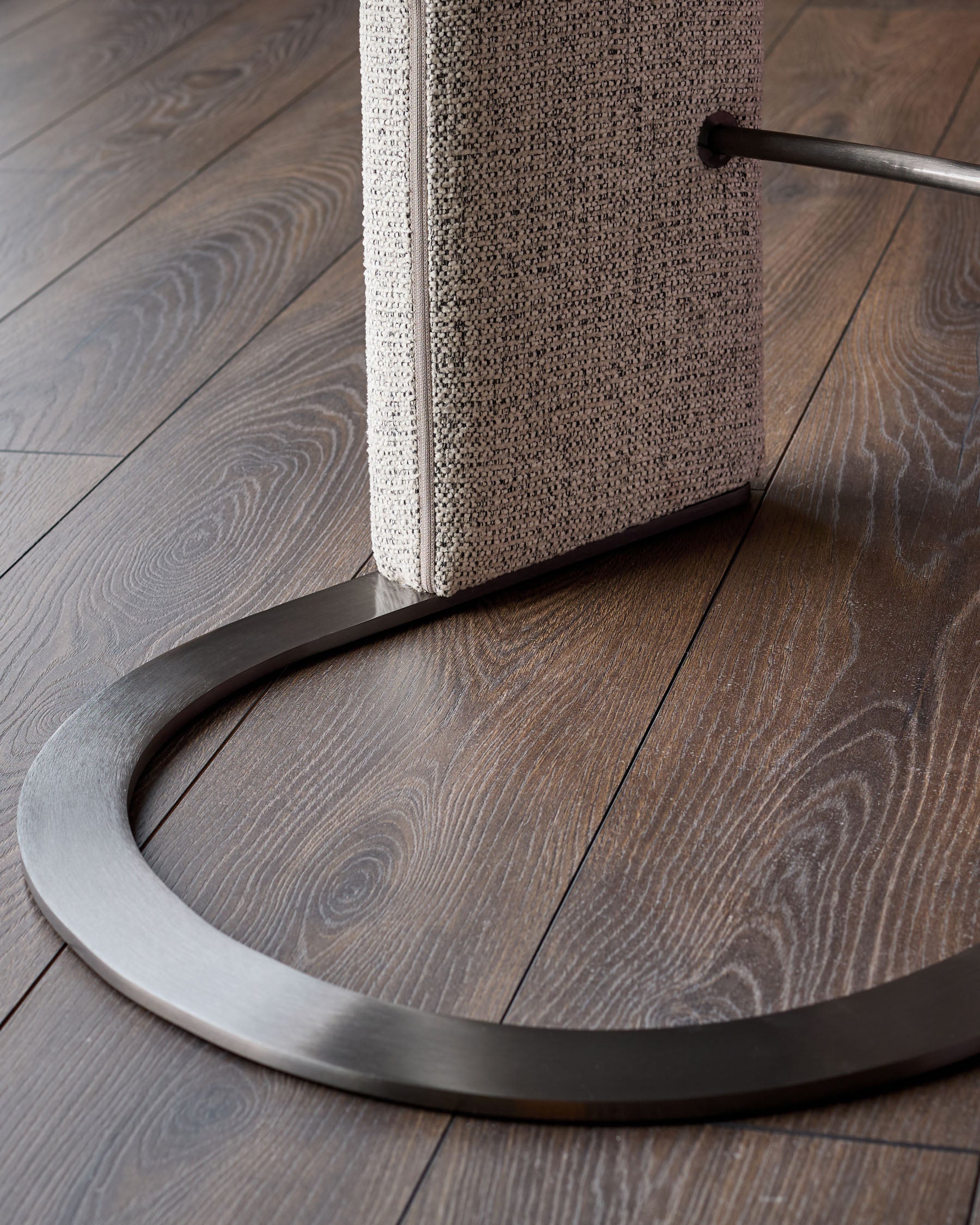 Leighton black steel cantilever bar stool with grey fabric seat, showing curved metal base and backrest detail on wood flooring.