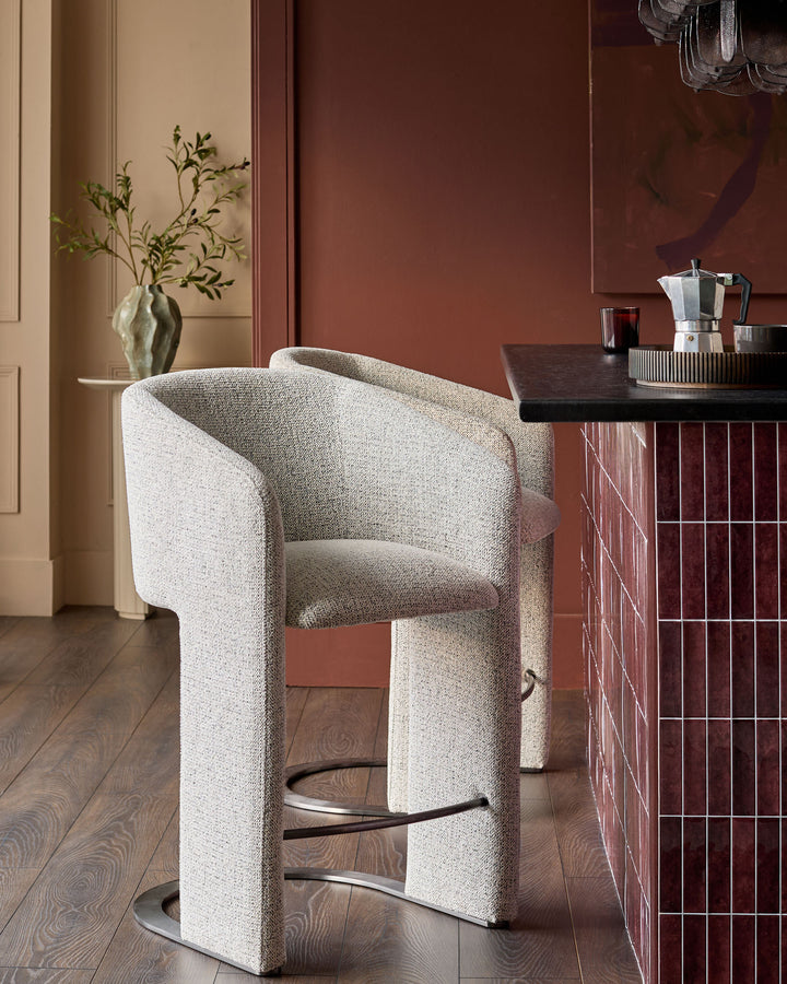 Leighton bar stool in grey fabric with black steel cantilever base, positioned at counter in modern interior setting.