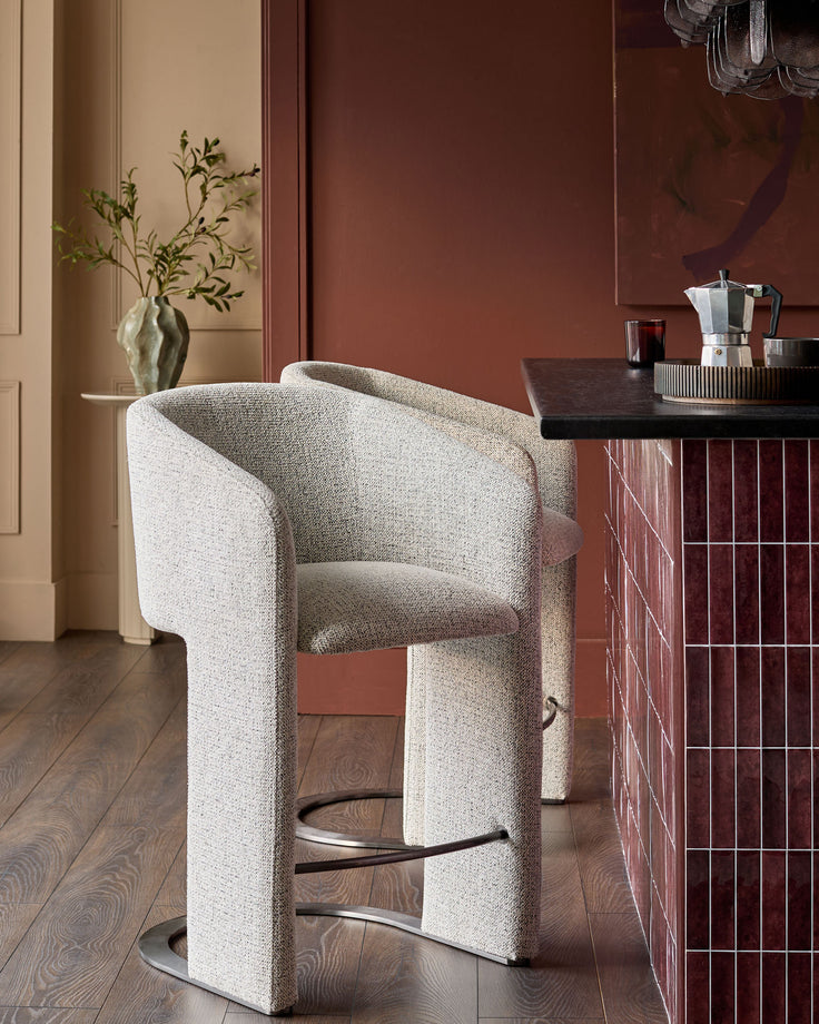 Leighton bar stool in grey fabric with black steel cantilever base, positioned at counter in modern interior setting.