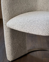 Leighton dining chair in grey chenille fabric, curved design, detail view of seat and backrest on dark wood floor.