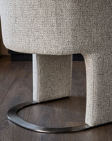 Leighton dining chair in grey chenille fabric with black chrome curved base, shown from low angle detail view.