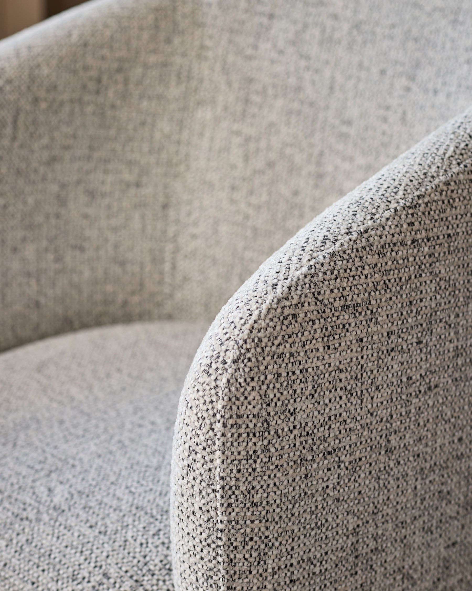 Close-up of grey chenille fabric on Leighton dining chair, showing textured weave and curved armrest detail.
