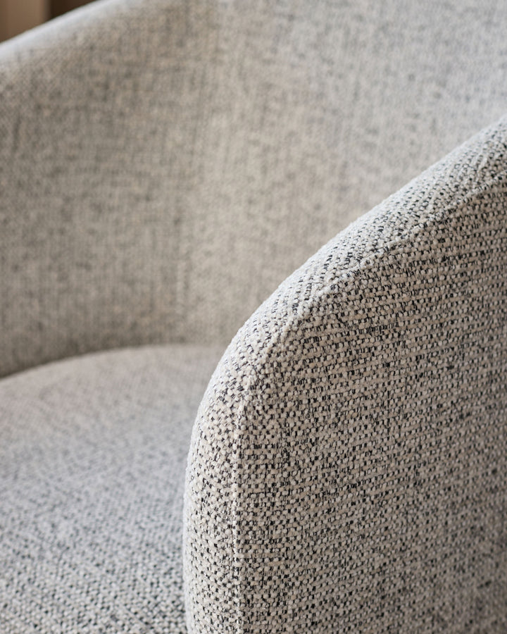 Close-up of grey chenille fabric on Leighton dining chair, showing textured weave and curved armrest detail.