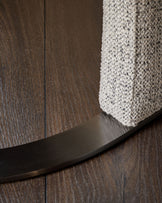 Leighton dining chair base detail showing black chrome curved leg against wood flooring and grey chenille fabric seat.