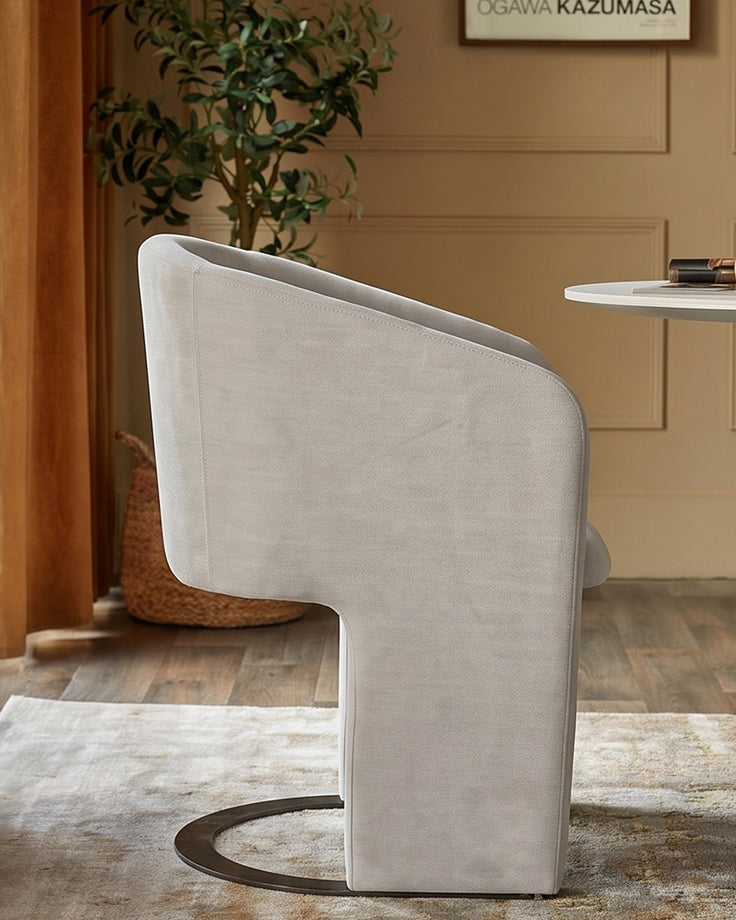 Leighton dining chair in natural grey chenille with black chrome curved base, shown from rear angle in styled interior setting.