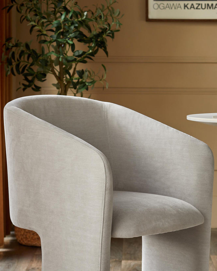 Leighton dining chair in natural grey chenille fabric, curved barrel shape with rounded backrest, side view.