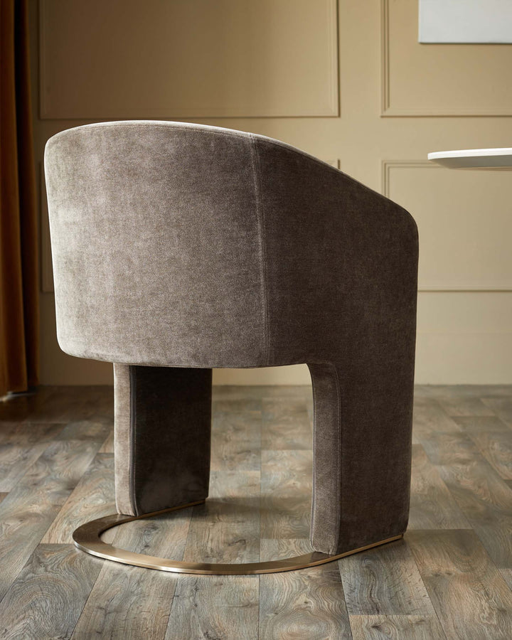 A contemporary velvet chair with a curved back and a gold base, adding a touch of elegance to any dining room.