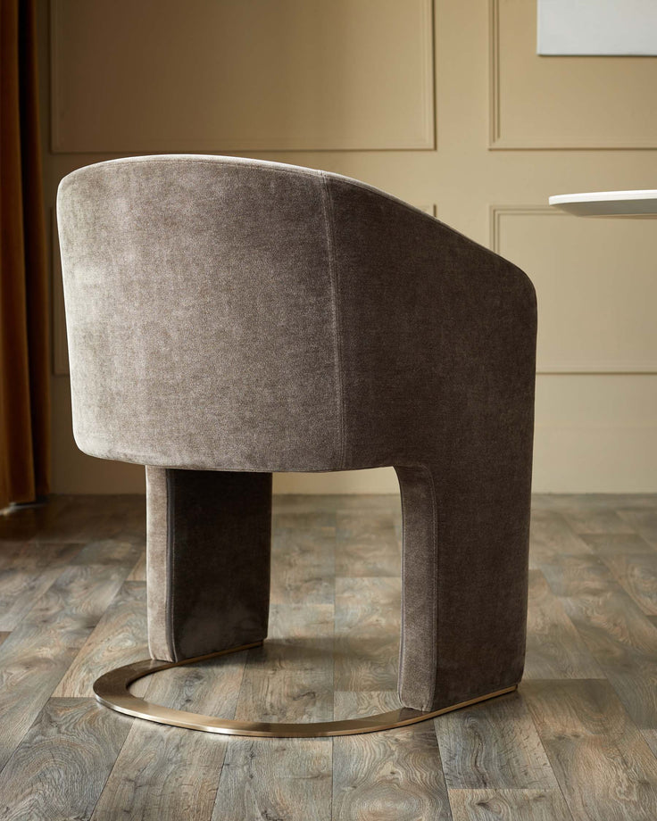 A contemporary velvet chair with a curved back and a gold base, adding a touch of elegance to any dining room.