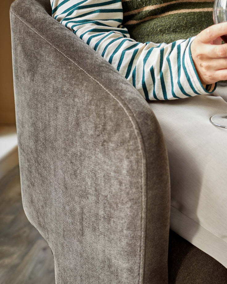 Close-up of a brown upholstered chair. The chair is textured and appears to be very comfortable.
