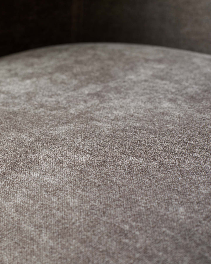 Close-up of a textured, brown upholstered seat, showcasing the fabric's detail and soft appearance.