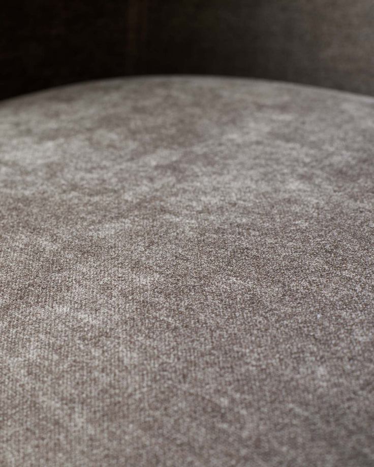 Close-up of a textured, brown upholstered seat, showcasing the fabric's detail and soft appearance.