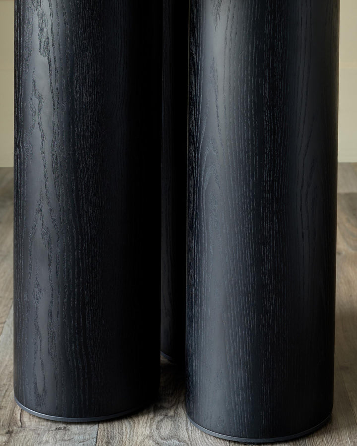 Close-up of three black, wooden side tables with a cylindrical design, showcasing their textured finish.