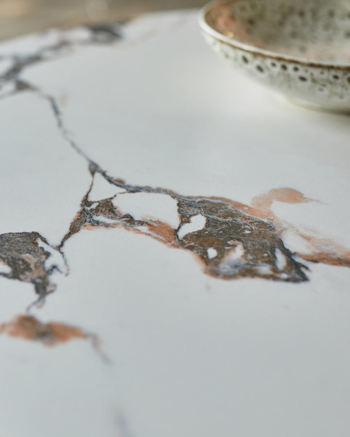 Close-up of a marble-effect countertop with a decorative ceramic bowl. Focus on the intricate veining.
