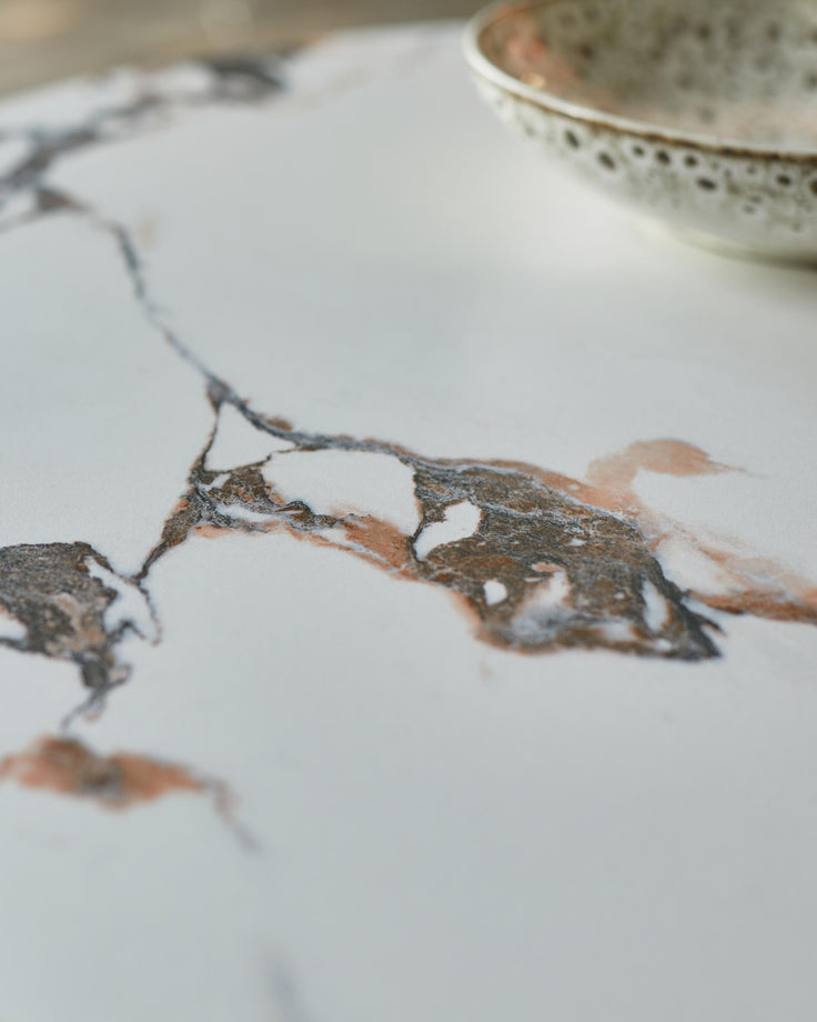 Close-up of a marble-effect countertop with a decorative ceramic bowl. Focus on the intricate veining.