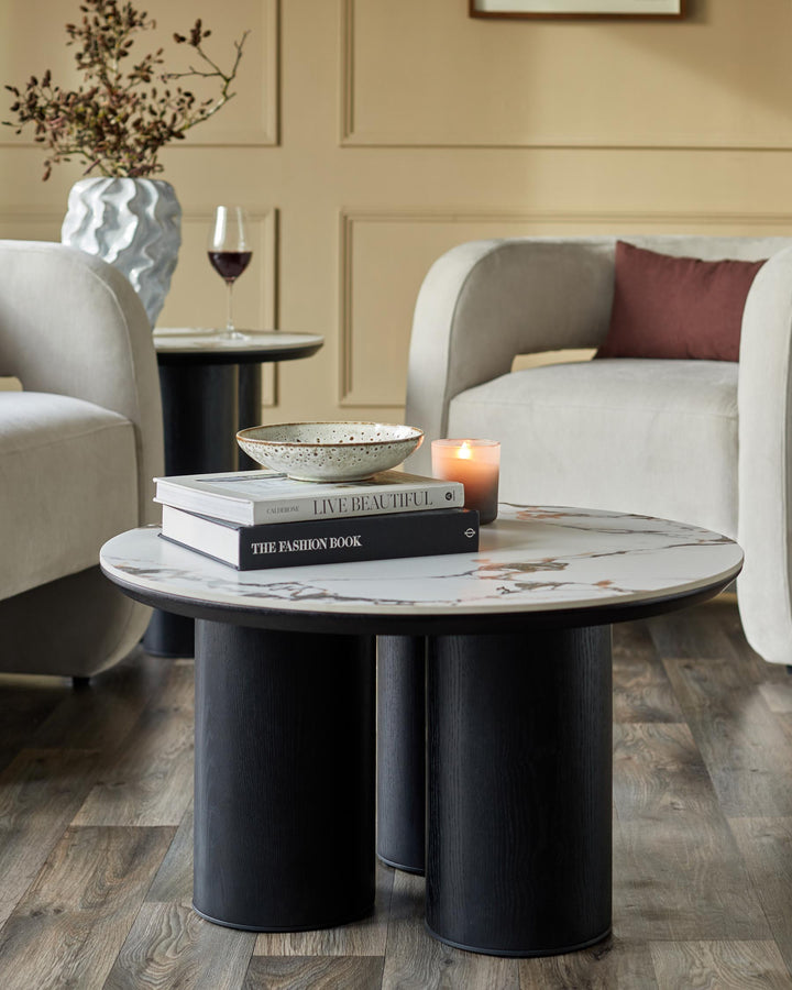 Stylish living room furniture featuring a coffee table, side table, vase, books and two armchairs.