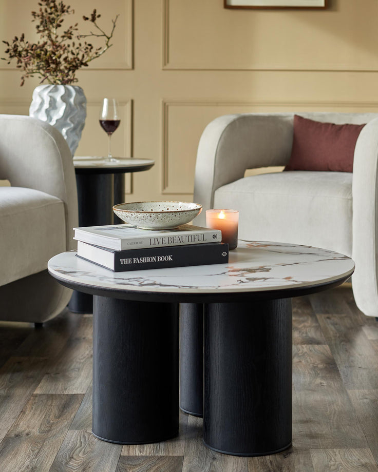 Stylish living room furniture featuring a coffee table, side table, vase, books and two armchairs.