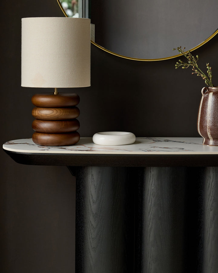 Lena console table in Calacatta white with dark wood base, styled with wooden lamp and ceramic accessories.