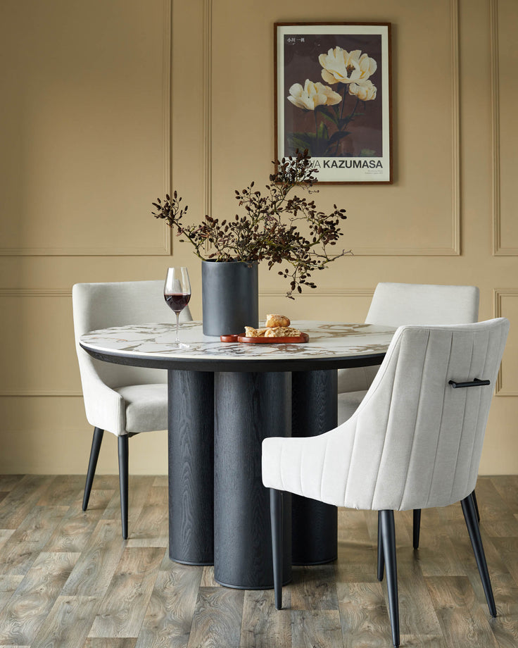 Stylish dining set featuring a round marble table, supported by a modern grey base, complemented by elegant upholstered chairs.