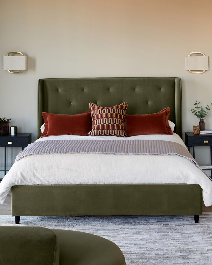 A stylish bedroom setup with an olive green bed, colourful cushions and bedside tables with lamps.