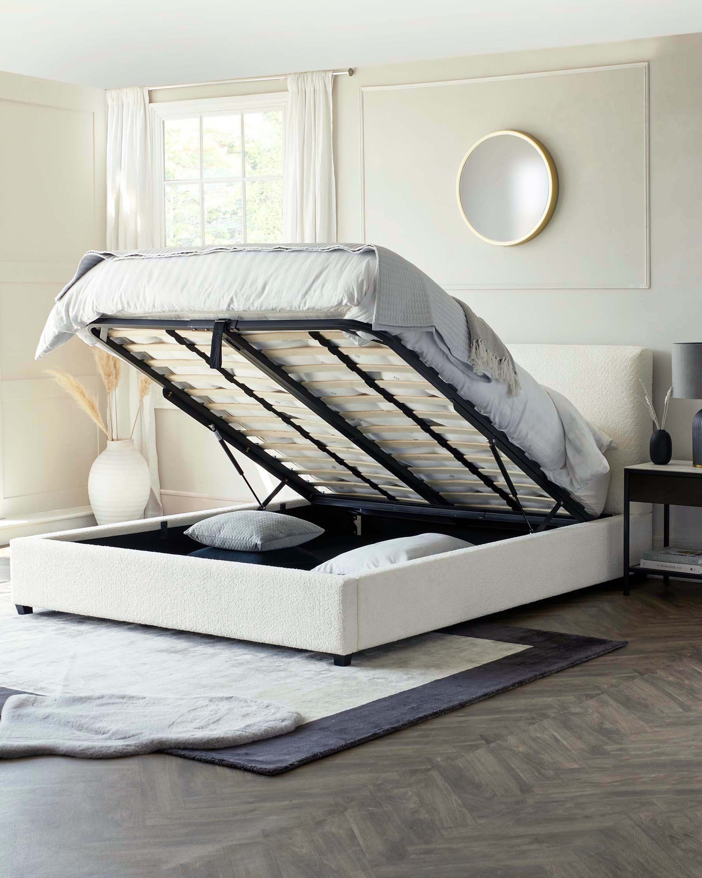 Modern upholstered storage bed with a raised mattress platform revealing a spacious under-bed storage area, set in a contemporary bedroom setting.