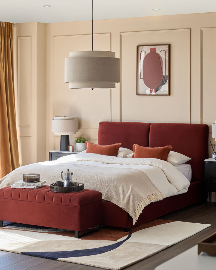 A luxurious red bed with bedside tables, footstool and a stylish rug. A cosy and inviting bedroom scene.