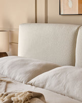 Close-up of a stylish bed with a textured headboard, soft pillows, and a cosy blanket for a serene bedroom setting.
