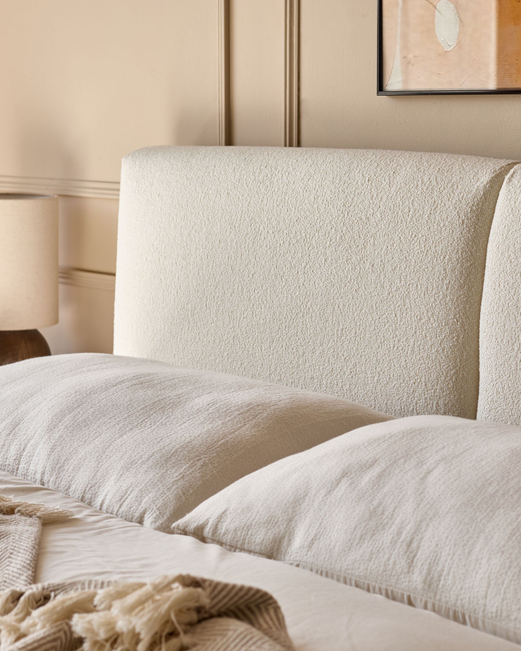 Close-up of a stylish bed with a textured headboard, soft pillows, and a cosy blanket for a serene bedroom setting.