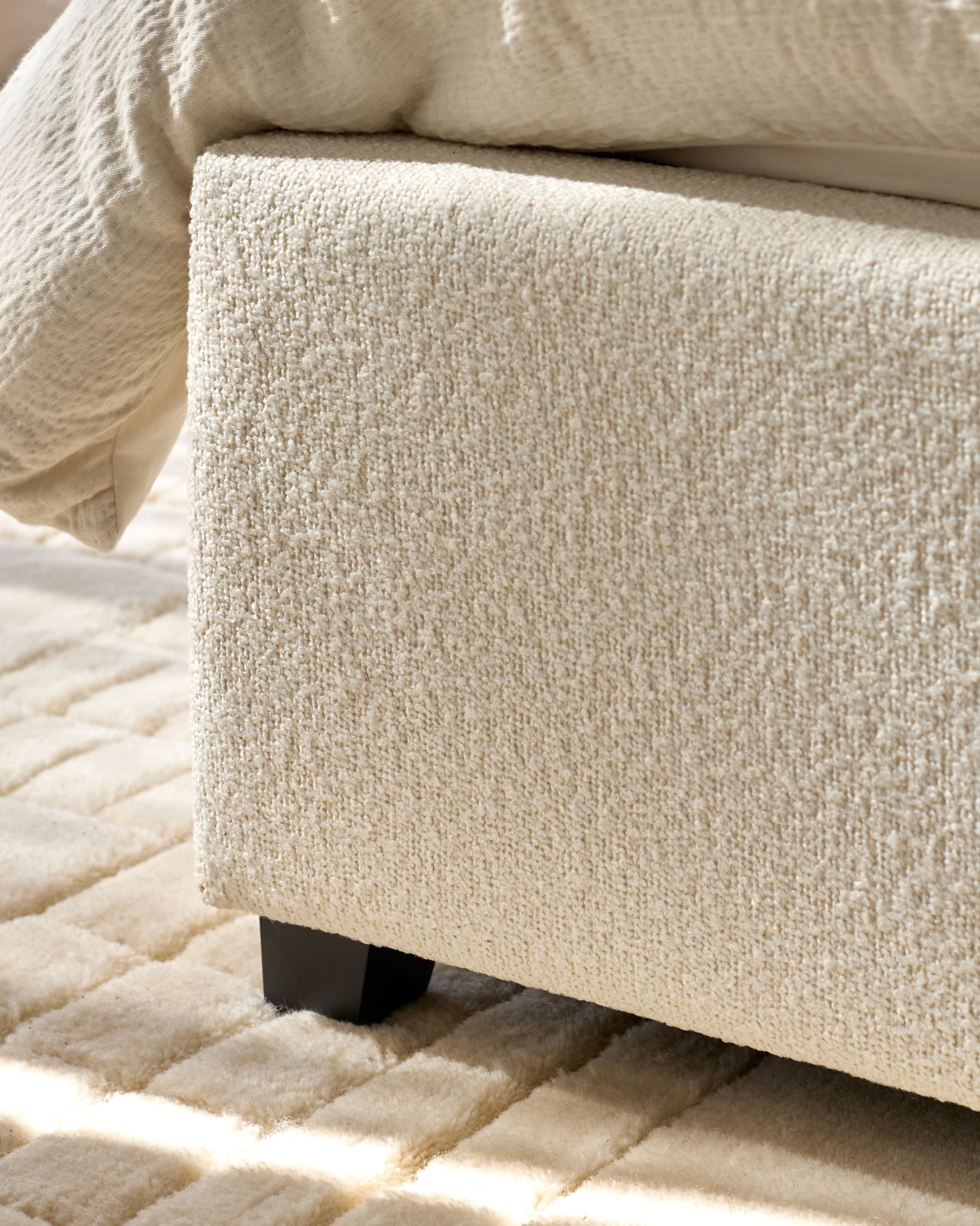 Close-up of a stylish neutral armchair with textured fabric, resting on a plush patterned rug.