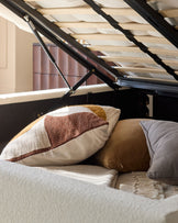 A lift-up storage bed with pillows, showing the frame and storage space underneath, useful for a small bedroom.