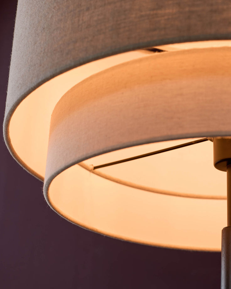 Leonie floor light with natural linen shade and mocha base, close-up detail showing curved shade and warm glow.