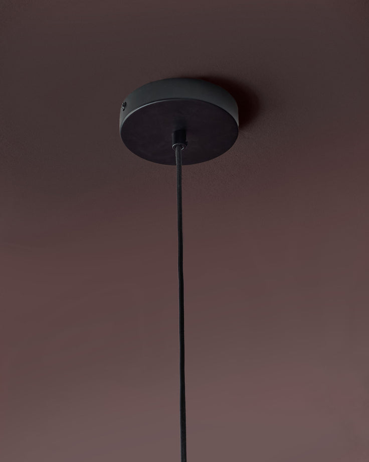 Black pendant light with long cord, ceiling canopy detail visible against mauve wall.