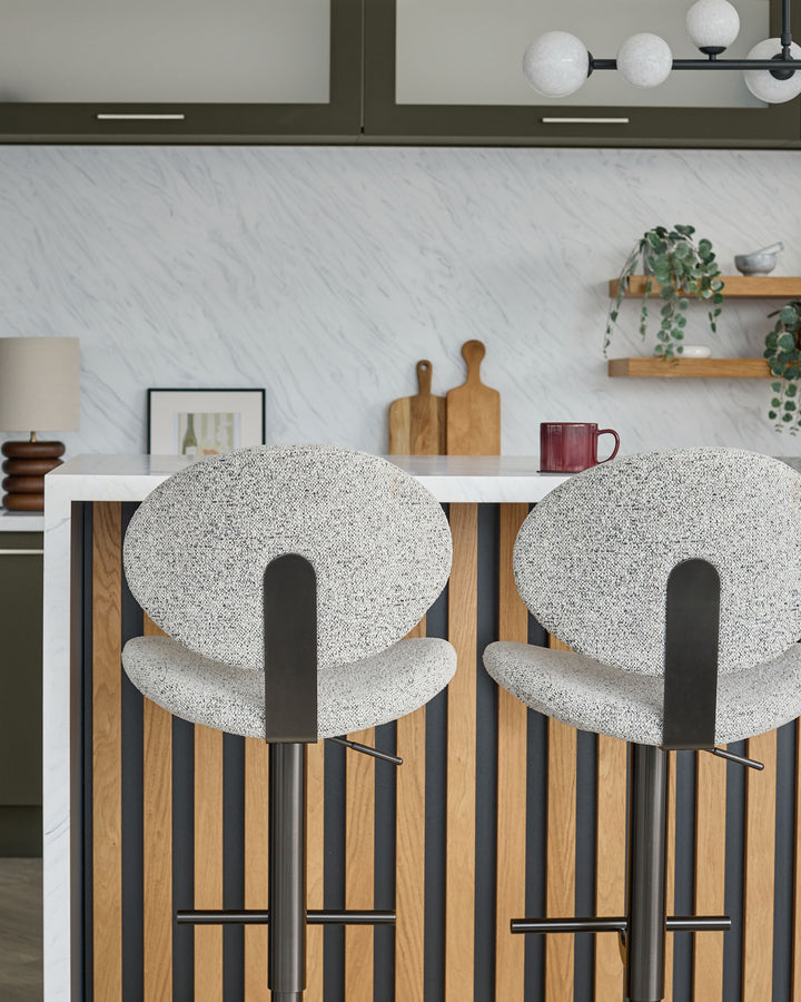 Lilah grey fabric bar stools with black metal frames and wood-look legs, shown at kitchen counter.