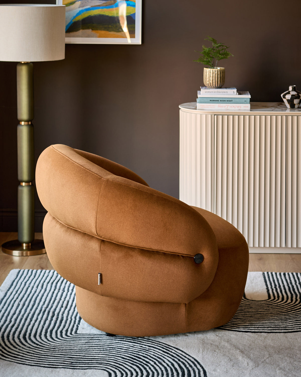 Lillian accent chair in caramel fabric, showcasing its distinctive rounded, cocoon-like silhouette in a styled living room setting.