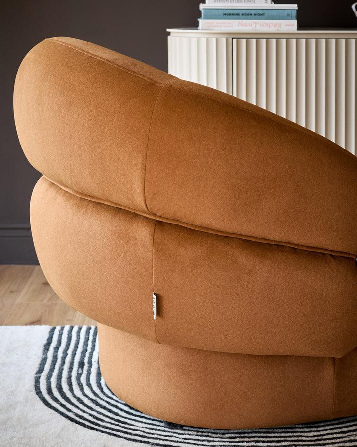 Lillian accent chair in caramel fabric, angled back view showing curved rounded silhouette and quilted seam details.