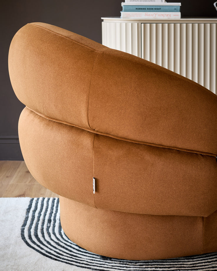 Lillian accent chair in caramel fabric, angled back view showing curved rounded silhouette and quilted seam details.