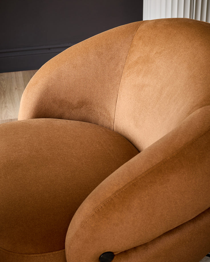 Lillian accent chair in caramel fabric, showing curved rounded silhouette and upholstered design from side angle.